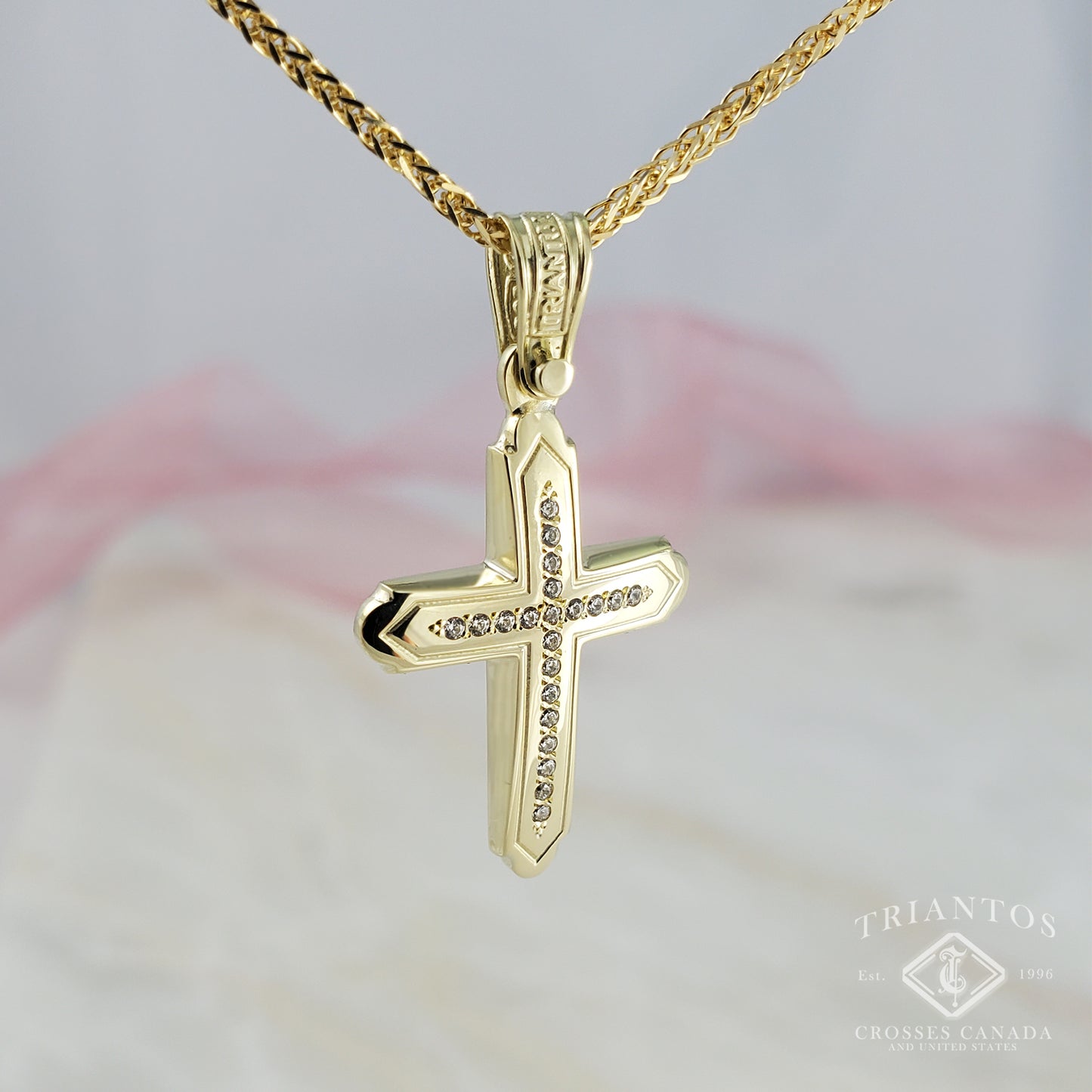 Woman's yellow gold cross pendant centered with 21 Sparkling cubic zirconia diamond-shaped stones and edged outline